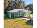 Attractive one-story home boasts teal siding, metal roof, and inviting, covered front porch at 9330 Se 106Th Pl, Belleview, FL 34420