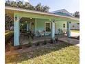 Inviting covered front porch with teal columns, outdoor lighting, and comfortable seating area at 9330 Se 106Th Pl, Belleview, FL 34420