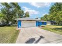 Bright blue home featuring an attached garage, ample parking, and a well-manicured lawn at 11 Se Fir Trail Trak, Ocala, FL 34472