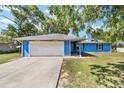 Front exterior of a cozy blue single-story home with a two car attached garage and spacious driveway at 11 Se Fir Trail Trak, Ocala, FL 34472