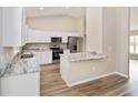 Modern kitchen featuring white cabinetry, stainless steel appliances, and granite countertops with a breakfast bar at 1143 Sw Tamiami Pl, Dunnellon, FL 34431