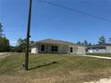 Single-story home with a well-manicured lawn and attached garage, with lush surrounding trees and a blue sky at 14443 Sw 21St Pl, Ocala, FL 34481
