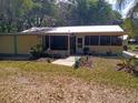 Cozy yellow home featuring a screened porch, metal roof, and lush greenery creating a peaceful and inviting outdoor space at 22736 Sw 117Th St, Dunnellon, FL 34431