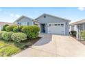 Charming single-story home with a two-car garage, lush landscaping, and a concrete driveway under a blue sky at 2296 Sheehan St, The Villages, FL 32163