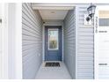 Close-up of the light gray home's front door with a decorative glass window, welcome mat and house numbers at 2296 Sheehan St, The Villages, FL 32163