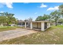Single-story home with a screened porch, covered carport, and lush greenery at 705 Washington Ave, Eustis, FL 32726