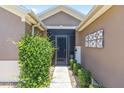 The entrance of a house with brown walls, a decorative door, and well-maintained landscaping at 7333 Sw 98Th Ct, Ocala, FL 34481