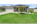 Well-maintained lawn and landscaped garden accent this gray home, complete with a two-car garage for convenience at 16192 Se 104Th Ter, Summerfield, FL 34491
