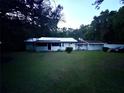 A single-story home with a metal roof and a screened porch, set against a backdrop of trees and a spacious front lawn at 2409 Nw 7Th St, Ocala, FL 34475