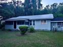 Quaint single-story home featuring a screened porch and durable metal roof, complemented by neatly manicured greenery at 2409 Nw 7Th St, Ocala, FL 34475