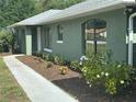 Freshly mulched landscape with a diverse variety of colorful plants, and an arched window adorn the exterior of the home at 4911 Se 135Th Pl, Summerfield, FL 34491