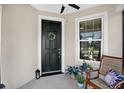 Cozy porch featuring a black front door with wreath and a chair next to a large window at 6051 Sw 93Rd Cir, Ocala, FL 34481