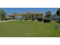 Charming single-story home featuring a lush green lawn, manicured shrubs, and an attached two-car garage, perfect for comfortable living at 9068 Se 120Th Loop, Summerfield, FL 34491