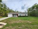 Quaint single-story home with a driveway, lush green lawn, and a manicured shrub in front at 120 Fisher Ct, Ocklawaha, FL 32179