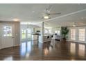 Spacious open-concept living area with hardwood floors, ceiling fans, large windows, and modern kitchen at 1228 Maria Ct, Lady Lake, FL 32159