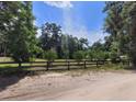 Beautiful backyard with a wood fence enclosing a grassy area and mature trees in the background at 13385 Ne 10Th Ct, Citra, FL 32113