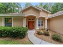 Charming front entryway with an orange door, white pillars, and manicured landscaping at 18328 Sw 73Rd Loop, Dunnellon, FL 34432