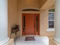 Close-up of the beautiful orange front door with sidelights and decorative transom window at 18328 Sw 73Rd Loop, Dunnellon, FL 34432