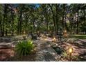 Backyard firepit area featuring stone pathway, outdoor furniture, and wooded backdrop at 200 Se 145Th St, Summerfield, FL 34491