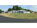 Inviting single-story light blue home with a well-kept lawn, complemented by lush landscaping and shade trees at 2909 Ne 25Th St, Ocala, FL 34470