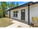 Close-up of the front door of a home with a black door and trim and a concrete walkway at 4095 Sw 144Th St, Ocala, FL 34473