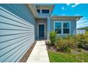 Inviting entryway with a modern blue door, manicured landscaping, and complementary exterior paint at 5621 Sw 90Th Ln, Ocala, FL 34476