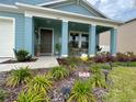 Home's inviting front yard showcases colorful landscaping and a welcoming porch area with stylish decor at 5667 Sw 92Nd Pl, Ocala, FL 34476