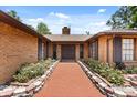 Inviting front entrance with double doors, brick accents, and lush landscaping along the red brick walkway at 6157 Ne 25Th Ave, Ocala, FL 34479