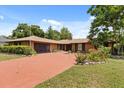 Lovely brick home with a red driveway, mature trees, and landscaping adding to the curb appeal at 6157 Ne 25Th Ave, Ocala, FL 34479
