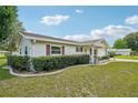 Inviting single-story home showcasing a well-kept lawn, decorative landscaping, and a classic facade with red shutters at 6448 Sw 111Th Pl, Ocala, FL 34476