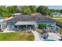Aerial view of a patio with a table, chairs, and potted plants overlooking a pool and a manicured backyard at 7 Larch Dr, Ocala, FL 34480