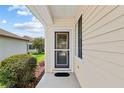Close-up of front door with screen door, covered entry, and manicured landscaping at 9408 Se 132Nd Loop, Summerfield, FL 34491