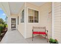 Inviting front porch with covered entry, charming bench, and well-maintained landscaping at 9408 Se 132Nd Loop, Summerfield, FL 34491