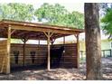 View of a wooden horse stall shelter and black horse; wooden fence and house in the background at 10208 Se 170 Pl, Summerfield, FL 34491