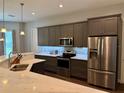 Bright kitchen features stainless steel appliances, gray cabinets, and lovely backsplash at 10208 Se 170 Pl, Summerfield, FL 34491