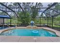 Screened-in pool features a basketball hoop and a blue inflatable tube at 14330 Sw 79Th Ter, Ocala, FL 34473