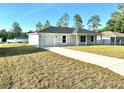 Well-maintained single-story home with attached garage, long driveway, and green front lawn at 14425 Sw 21St Pl, Ocala, FL 34481