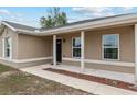 Close-up view of the home's entrance with supporting columns and a neutral-tone exterior with white trim around the windows at 2690 Sw 154Th Ln, Ocala, FL 34473