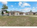 Wide shot of a single-story home featuring a neutral-toned exterior with a green yard surrounded by a chain-link fence at 2690 Sw 154Th Ln, Ocala, FL 34473