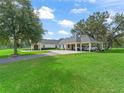 An expansive home featuring a covered portico and lush green lawn with a long paved driveway at 402 Sw 127Th Pl, Ocala, FL 34473