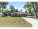 Charming single-story home with an expansive front lawn, long driveway, and attached two-car garage at 5425 Pecan Rd, Ocala, FL 34472