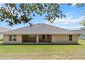 Back exterior showcasing a covered patio and well-maintained lawn, perfect for outdoor entertaining at 6680 Sw 179Th Court Rd, Dunnellon, FL 34432