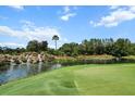 Scenic golf course view with a water feature, lush greenery, and clear blue skies at 6680 Sw 179Th Court Rd, Dunnellon, FL 34432