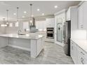 Modern kitchen boasts white cabinets, granite countertops, stainless steel appliances, and pendant lighting over a large island at 9777 Sw 63Rd Loop, Ocala, FL 34481