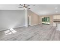 Open-concept living space with new gray flooring that adjoins the kitchen and has sliding glass doors to a large backyard at 174 Pine Crse, Ocala, FL 34472