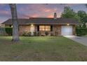 Charming brick home with a well-manicured lawn and attached one-car garage at sunset at 2819 Ne 32Nd Pl, Ocala, FL 34479