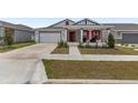 Beautiful house featuring a two-car garage, red door, covered porch and well-kept front yard at 6486 Sw 75Th Avenue Rd, Ocala, FL 34474