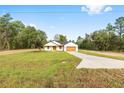 Single-story home with a sprawling green lawn, extended driveway, and a charming covered entryway at 8200 Sw 125Th Court Rd, Dunnellon, FL 34432