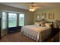 Cozy bedroom featuring a large bay window, ceiling fan, and a comfortable-looking bed at 9131 Se 135Th St, Summerfield, FL 34491