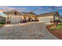 Charming single-story home at dusk, featuring a brick paved driveway and two-car garage in a well manicured yard at 9607 Sw 79Th Lane Rd, Ocala, FL 34481